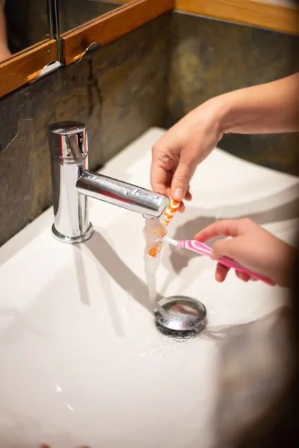 A young man is handling household cleaning, using a spray bottle to wipe down glass panels.